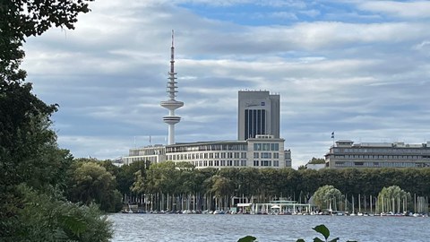 Foto eines Flusses, im Hintergrund ist ein Fernsehturm zu sehen.