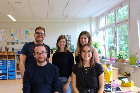 Gruppenbild mit drei Frauen und zwei Männern in einem Klassenzimmer