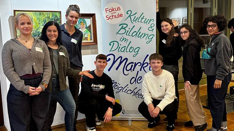 Gruppenbild mit 8 Personen um ein Roll-Up
