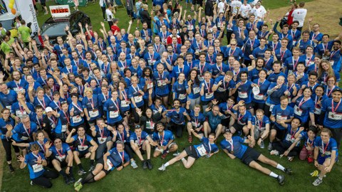 Foto zeigt eine riesige Gruppe von Menschen von oben fotografiert. Alle haben einheitliche blaue Sport-Shirts an.