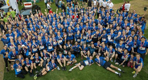 Foto zeigt eine riesige Gruppe von Menschen von oben fotografiert. Alle haben einheitliche blaue Sport-Shirts an.