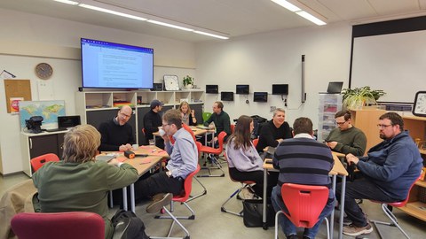 11 Personen sitzen in Kleingruppen zusammen während eines Worskhops.