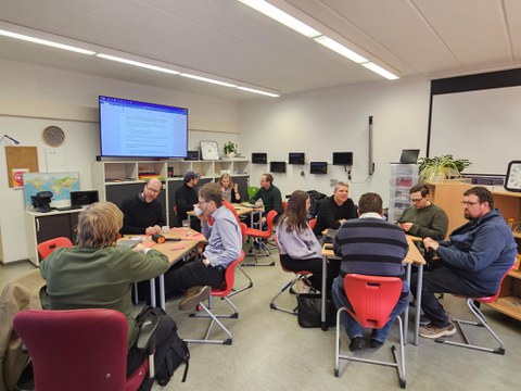 11 Personen sitzen in Kleingruppen zusammen während eines Worskhops.