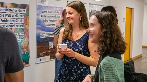 Zwei junge Frauen unterhalten sich und halten jeweils eine Tasse Kaffee in der Hand.