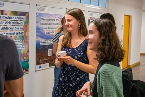 Zwei junge Frauen unterhalten sich und halten jeweils eine Tasse Kaffee in der Hand.