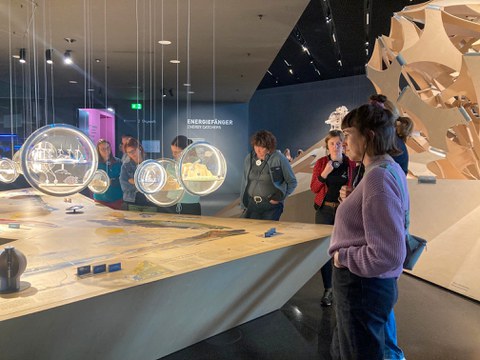 Ca. 10 Personen stehen um einen großen Tisch in einem Museum.