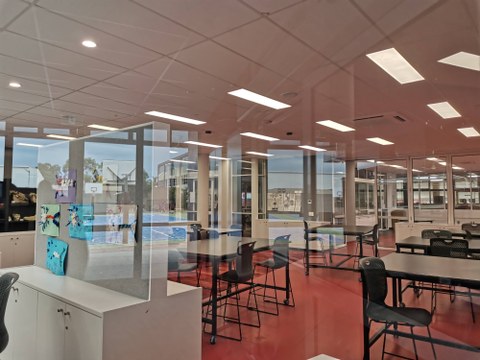 Das Bild zeigt einen großen Schulraum mit gläsernen Wänden.