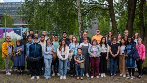 Gruppenbild mit ca. 30 Personen vor einem Baum.