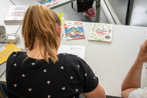 Foto zeigt Frau von oben, wie sie Lehrmaterialien an einem Tisch sichtet.