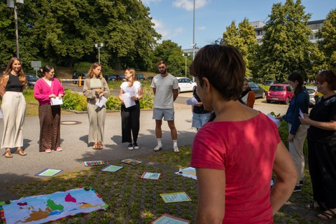 Frau hält Vortrag draußen vor einer Gruppe junger Erwachsener 