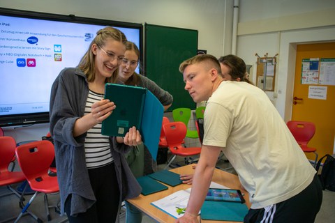 kleine Gruppe junger Menschen sieht zusammen in ein Tablet
