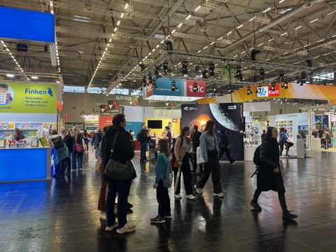 Zu sehen ist eine Messehalle, wo buntes Treiben herrscht
