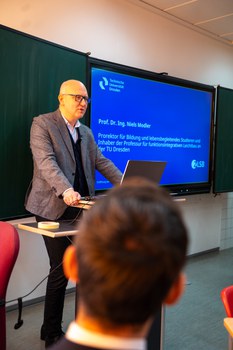 Mann hält Vortrag und steht dabei an einem Pult