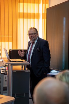 Mann hält Vortrag und steht dabei an einem Pult