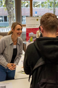 Frau unterhält sich mit Student an einem Beratungsstand