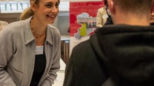 Frau unterhält sich mit Student an einem Beratungsstand