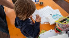 Kind stempelt etwas auf einem Blatt Papier
