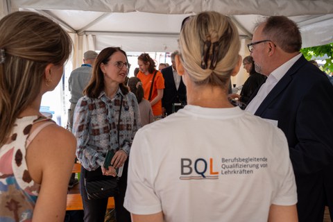 Man spricht mir Frau in einer Pagode. Im Vordergrund Tshirt mit BQL Logo zu sehen.