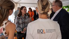 Man spricht mir Frau in einer Pagode. Im Vordergrund Tshirt mit BQL Logo zu sehen.