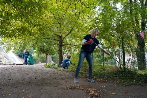 Frau im Vordergrund recht Laub, Im Hintergrund arbeiten zwei andere Frauen mit Laub