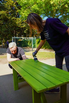 Frau und Mann streichen eine Holzbank