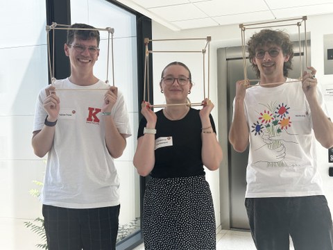 3 Studierende stehen mit Würfeln aus nachhaltigen Material in den Händen
