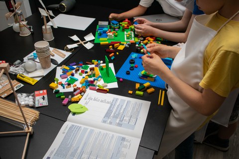 Nahaufnahme von Kinderhänden, wie sie gerade etwas mit Lego-Steinen bauen.