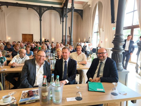 Auf dem Bild sieht man die Diskussionsteilnehmenden Prof. Dr. Axel Gehrmann, Michael Kretschmer und Christian Piwarz an einem Tisch sitzend beim Gewerkschaftstag des Sächsischen Lehrerverbandes am 23. August 2024.