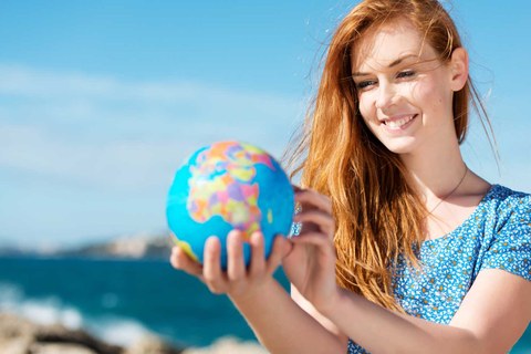 Eine lächelnde junge Frau, die auf einen kleinen globus schaut.