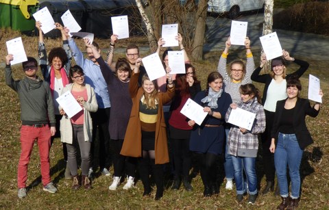 Bild einer Gruppe von 14 Studierenden, die jeweils ein Zertifikat in den Händen halten und in die Kamera lächeln
