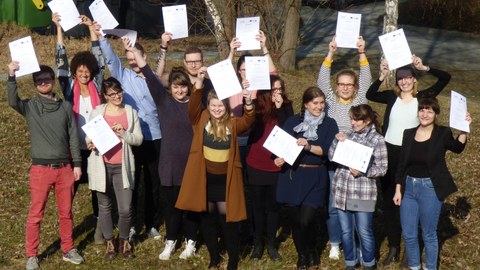 Bild einer Gruppe von 14 Studierenden, die jeweils ein Zertifikat in den Händen halten und in die Kamera lächeln