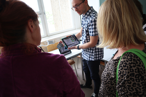 Eine studentische Hilfskraft zeigt die Anwendungsmöglichkeiten des Merge Cubes vor Publikum.