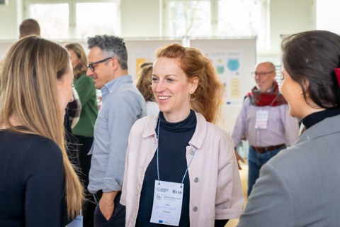 Eine Frau spricht mit anderen Konferenzteilnehmern.