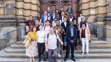 Eine Gruppe von ca. 20 Personen auf einer Treppe aufgereiht vor dem Eingang eines alten Ministeriumsgebäudes.