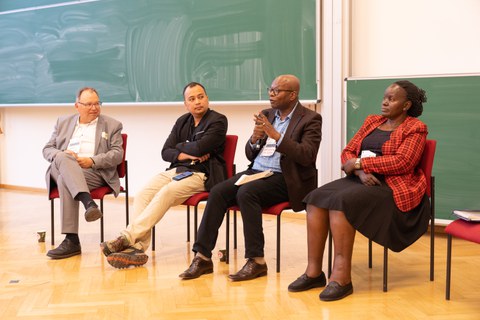 Das Foto zeigt vier Personen, die nebeneinander sitzen und auf einer Bühne miteinander diskutieren.