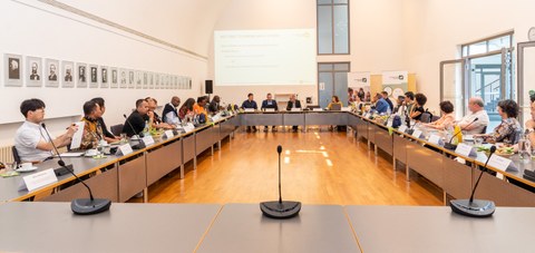 Das Foto zeigt einen Konferenzraum mit über 20 anwesenden Personen.