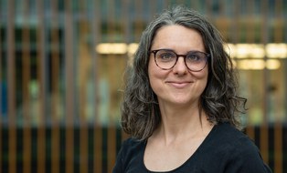 Portrait einer Frau mit schwarzen Haaren und Brille
