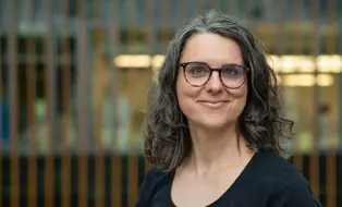 Portrait einer Frau mit schwarzen Haaren und Brille