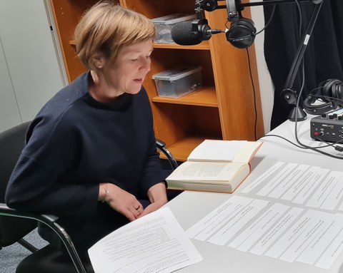 Frau sitzt vor Podcast-Mikrofon und spricht.