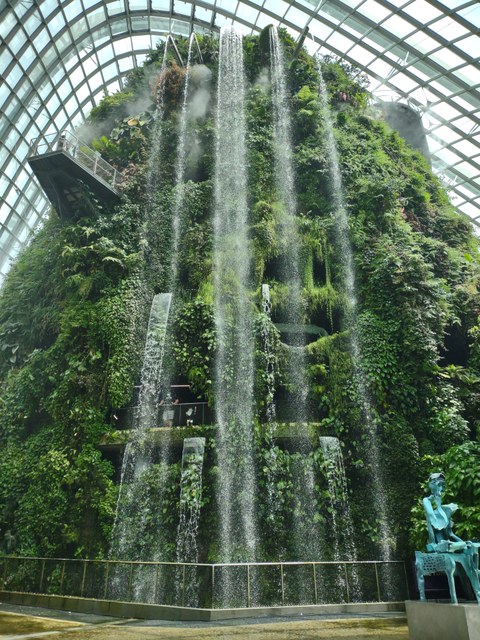 Grünfassade und Wasserfall unter einer Glaskuppel