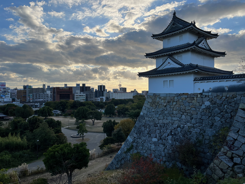 Auf der rechten Seite des Bildes ist ein traditionelles japanisches Gebäude zu sehen. im Hintergrund ist eine Stadt mit vielen Hochhäusern zu sehen.