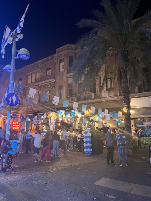 Foto einer belebten und blau-weiß dekorierten Gasse am Abend.