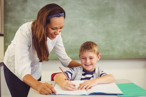 Eine Lehrerin hilft einem Schüler bei einer Aufgabe.