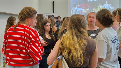 Foto von Personen, die sich intensiv Austauschen. Im Hintergrund ist die Projektion der Folie GetTUgether Lehramt zu sehen. 