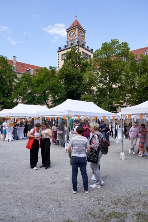 Ein Innenhof eines Unigebäudes mit vielen Informationsständen in Zelten; es herrscht buntes Treiben.