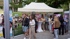 Ein Innenhof eines Unigebäudes mit vielen Informationsständen in Zelten; es herrscht buntes Treiben.