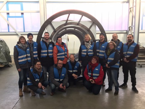 Foto: Gruppenbild von Personen in Warnwesten in einer Werkhalle