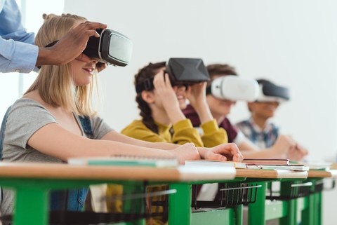 Foto: Kinder sitzen an Tisch und tragen VR-Brillen