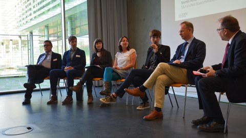 Bild von 7 Personen auf einer TUD-Sylber-Konferenz. Sie sitzen nebeneinander auf Stühlen und reden miteinander.