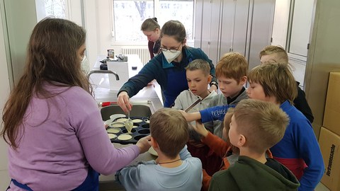 Foto: 9 Kinder und Jugendliche arbeiten gemeinsam in einer Küche.